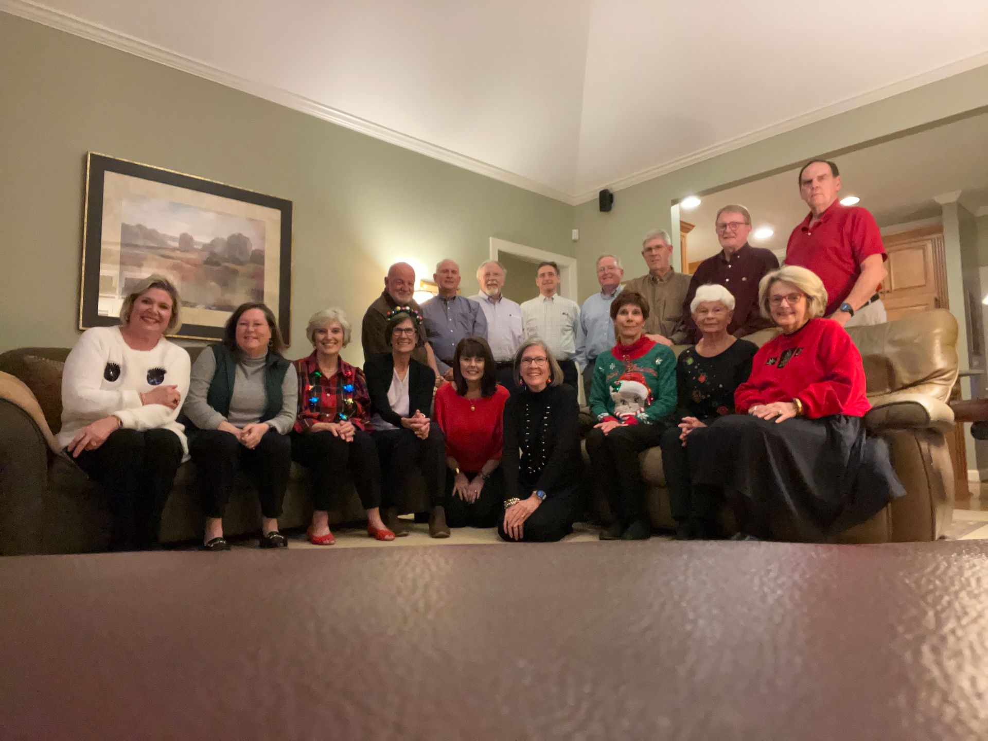 A group of older adults are sitting on a couch in a living room.