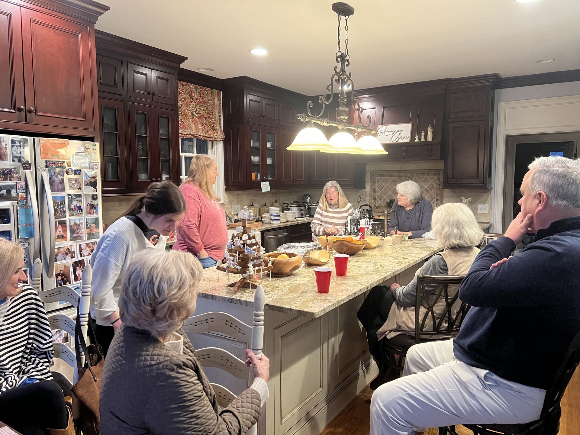 A small group of adults talking in a kitchen.
