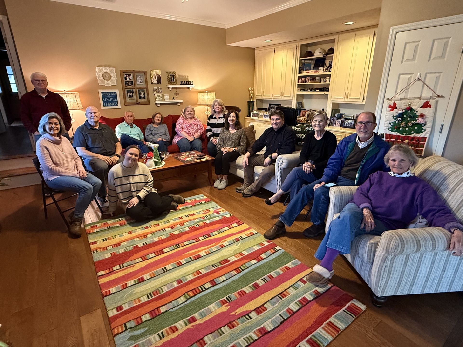 A group of older adults sit on couches in a living room.