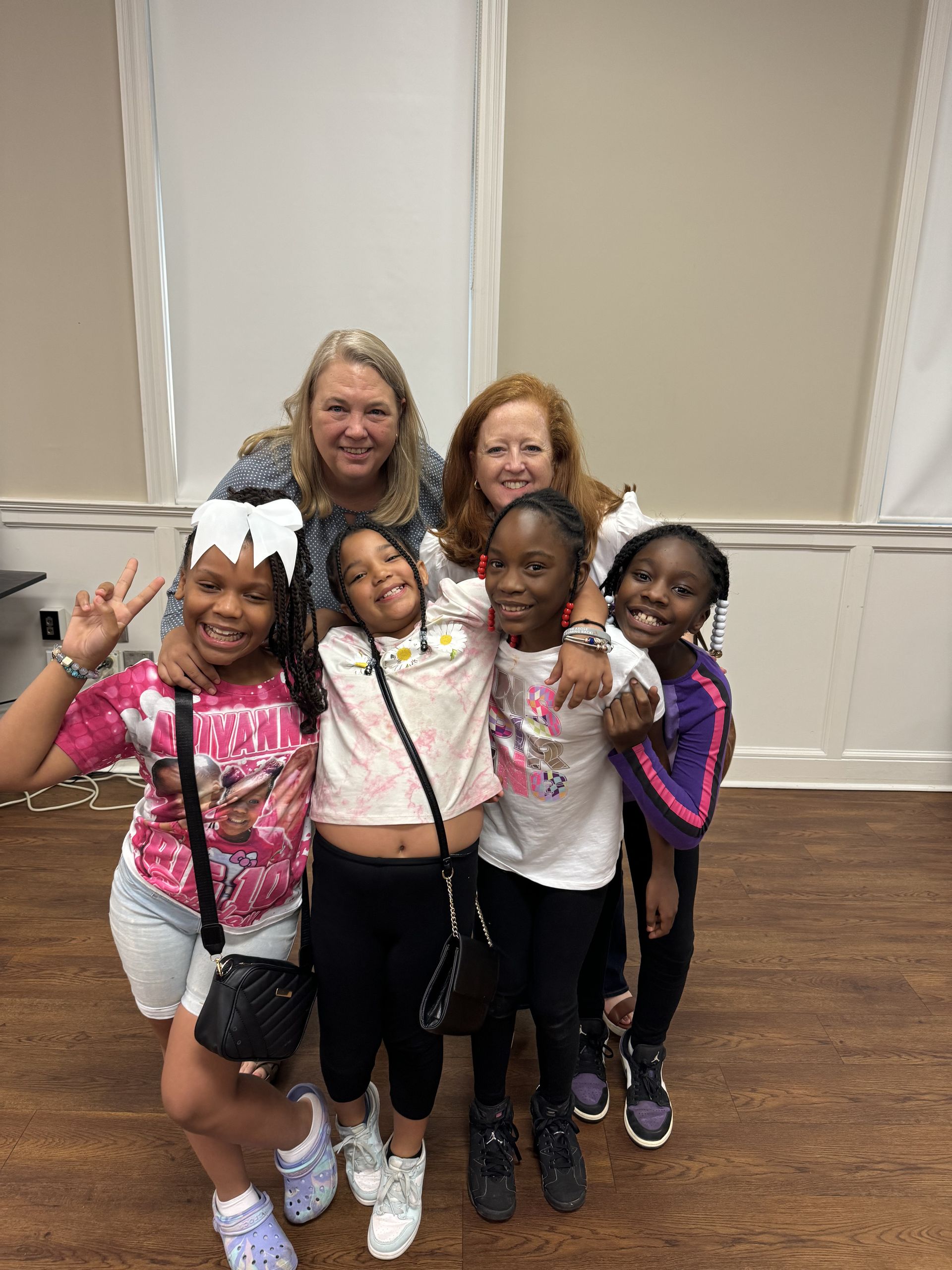 A group of young girls are posing for a picture with their teacher.
