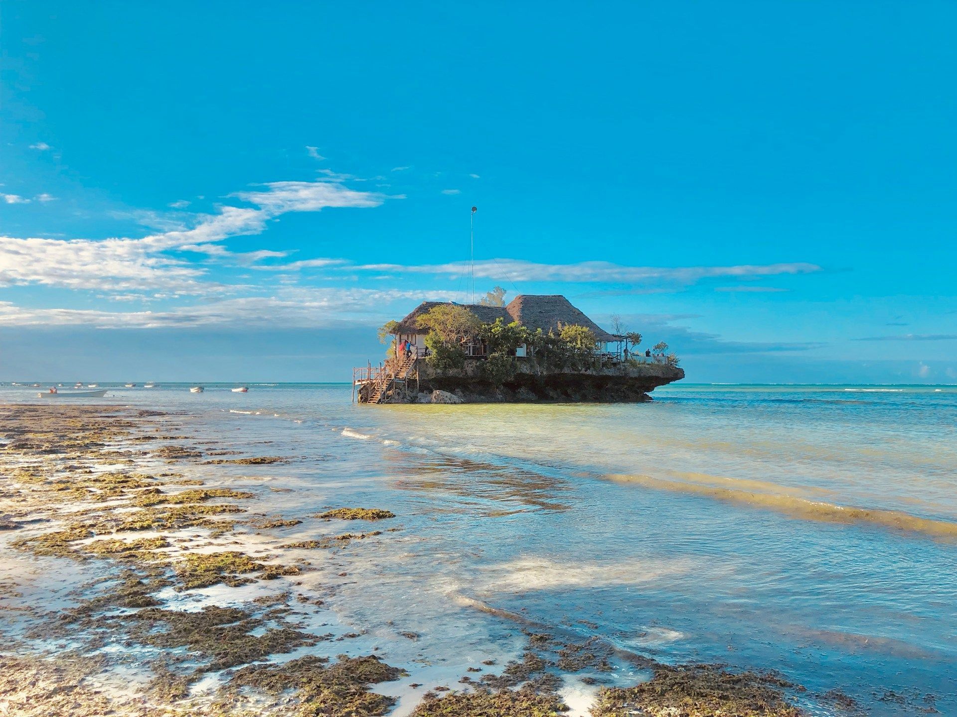 Rock restaurant in turquoise sea, Zanzibar, Tanzania, under a blue sky.