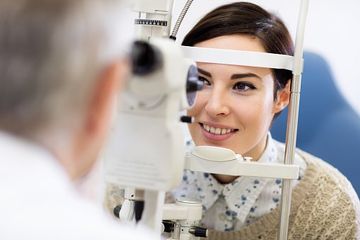 Woman look in ophthalmoscope - Eye Exams in South Gate, CA