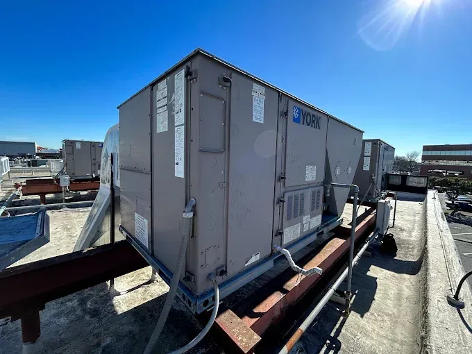 Rooftop air conditioning units on a building, under a bright, sunny sky.