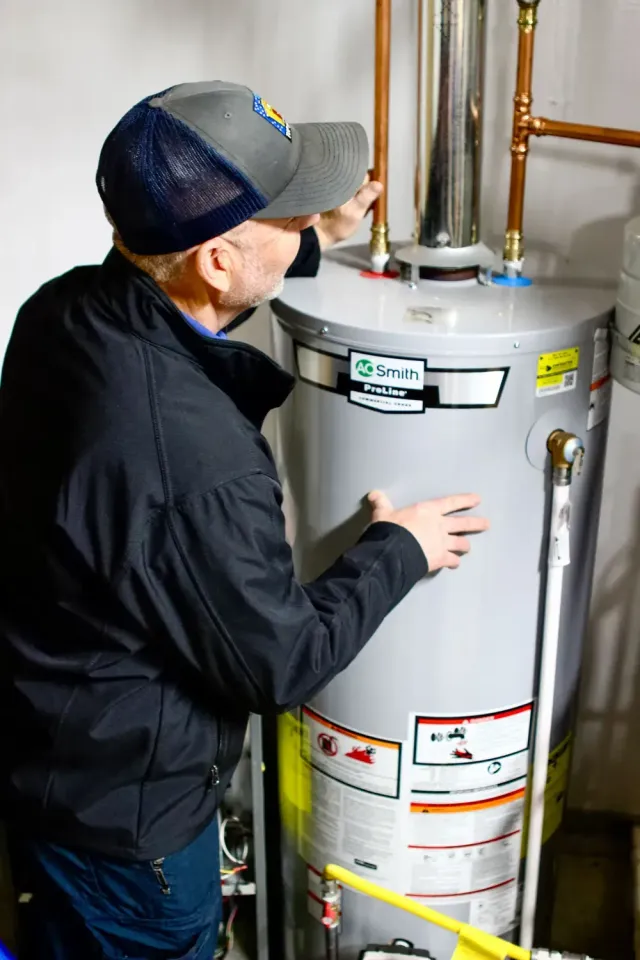 White Rheem tankless water heater in a green closet.