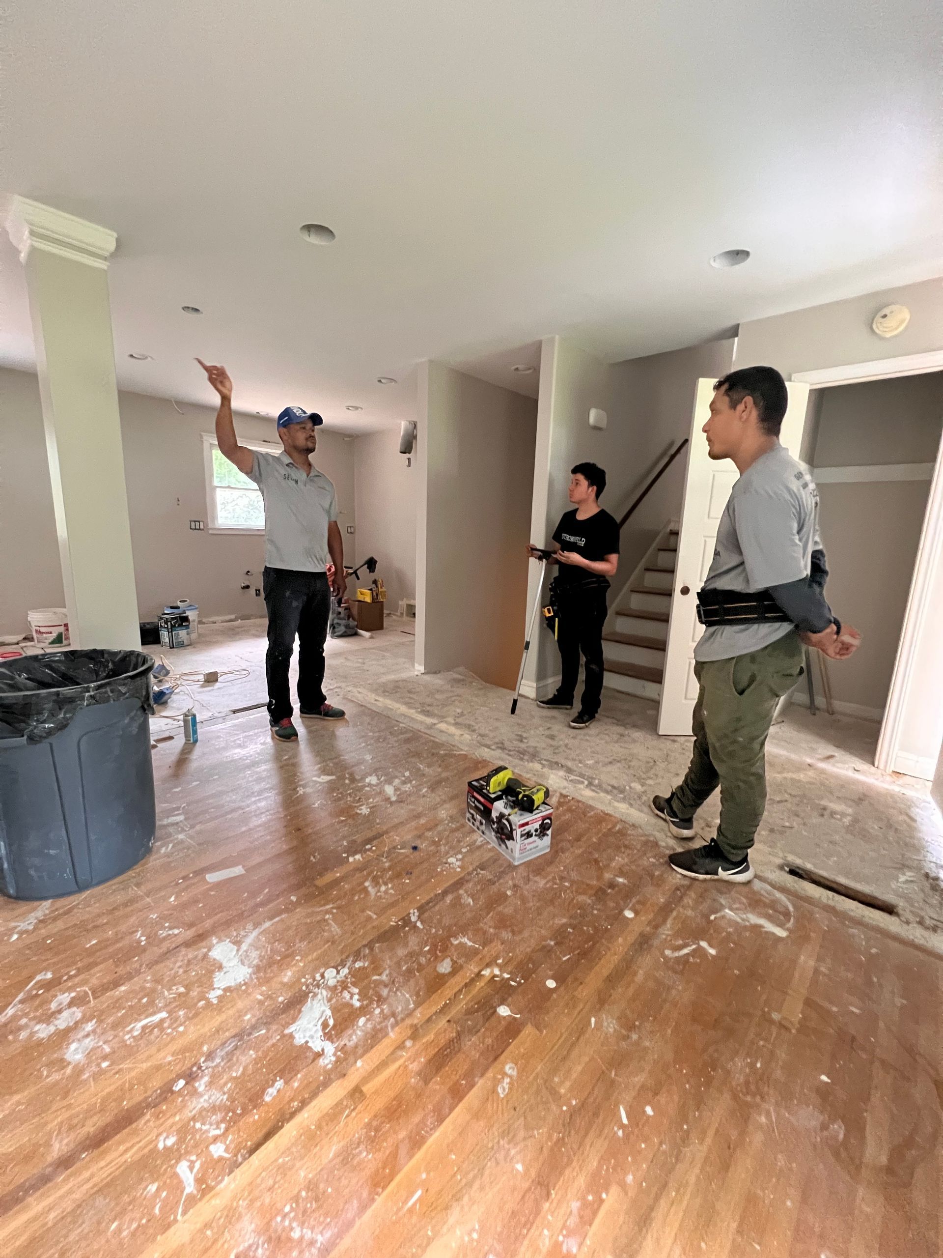 A group of people are standing in a messy room.