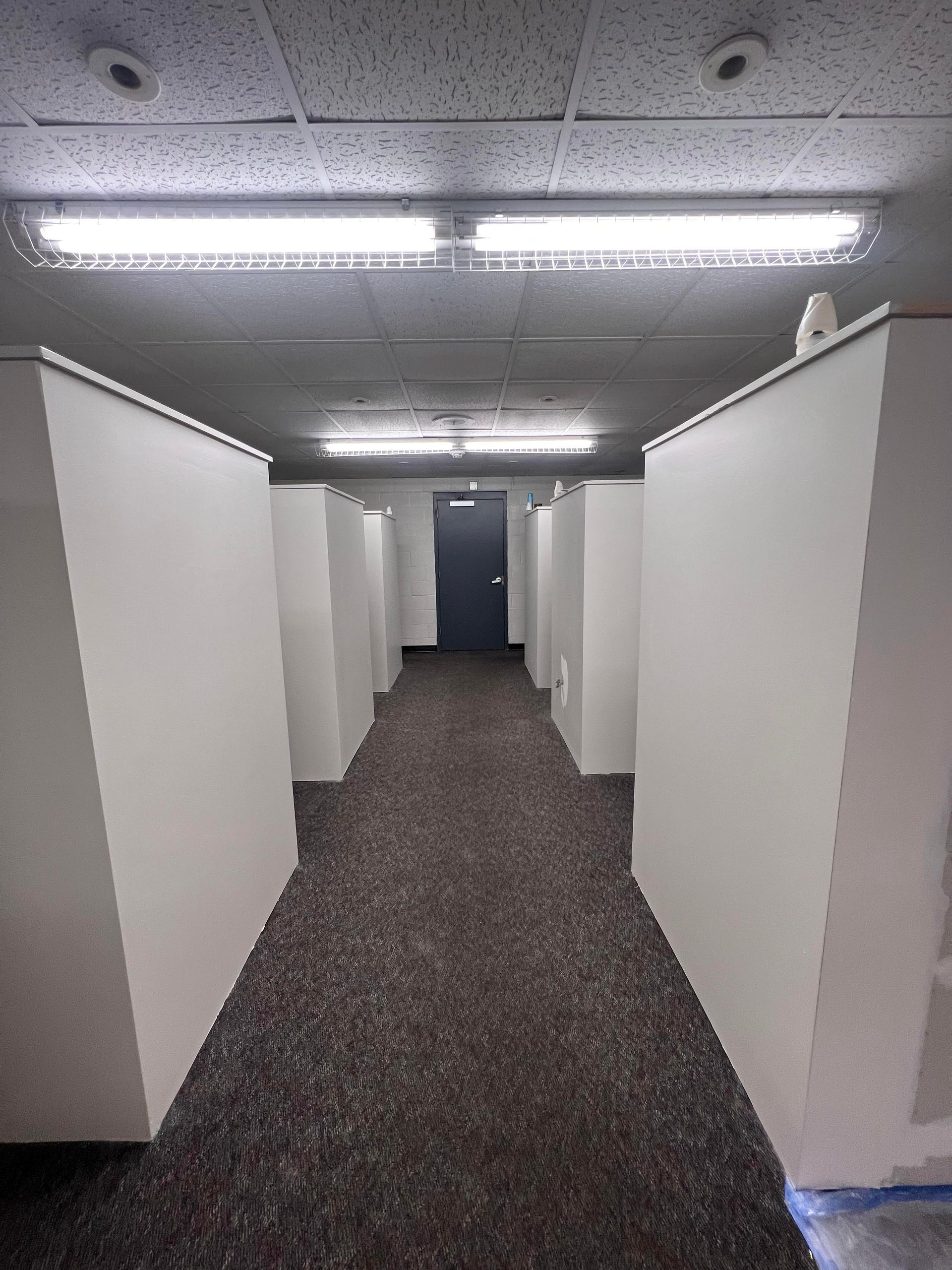 A long hallway with white walls and brown carpet