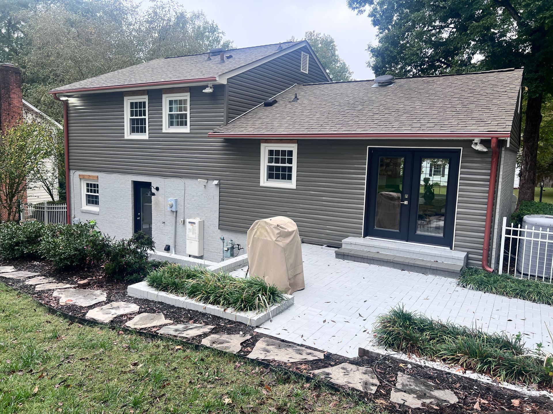 The back of a house with a patio and a walkway leading to it.