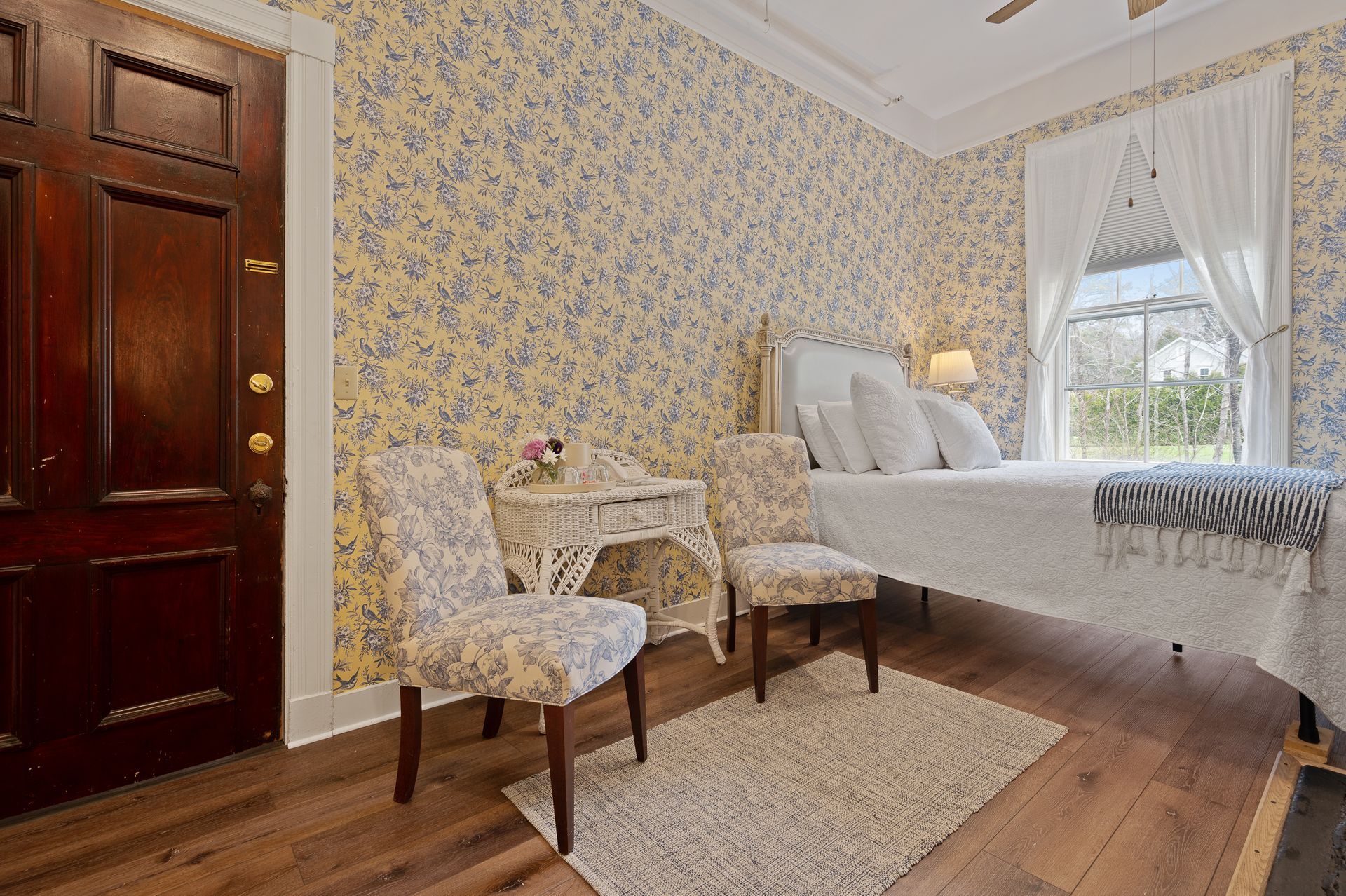 A bedroom with a bed , chairs , a table and a window.