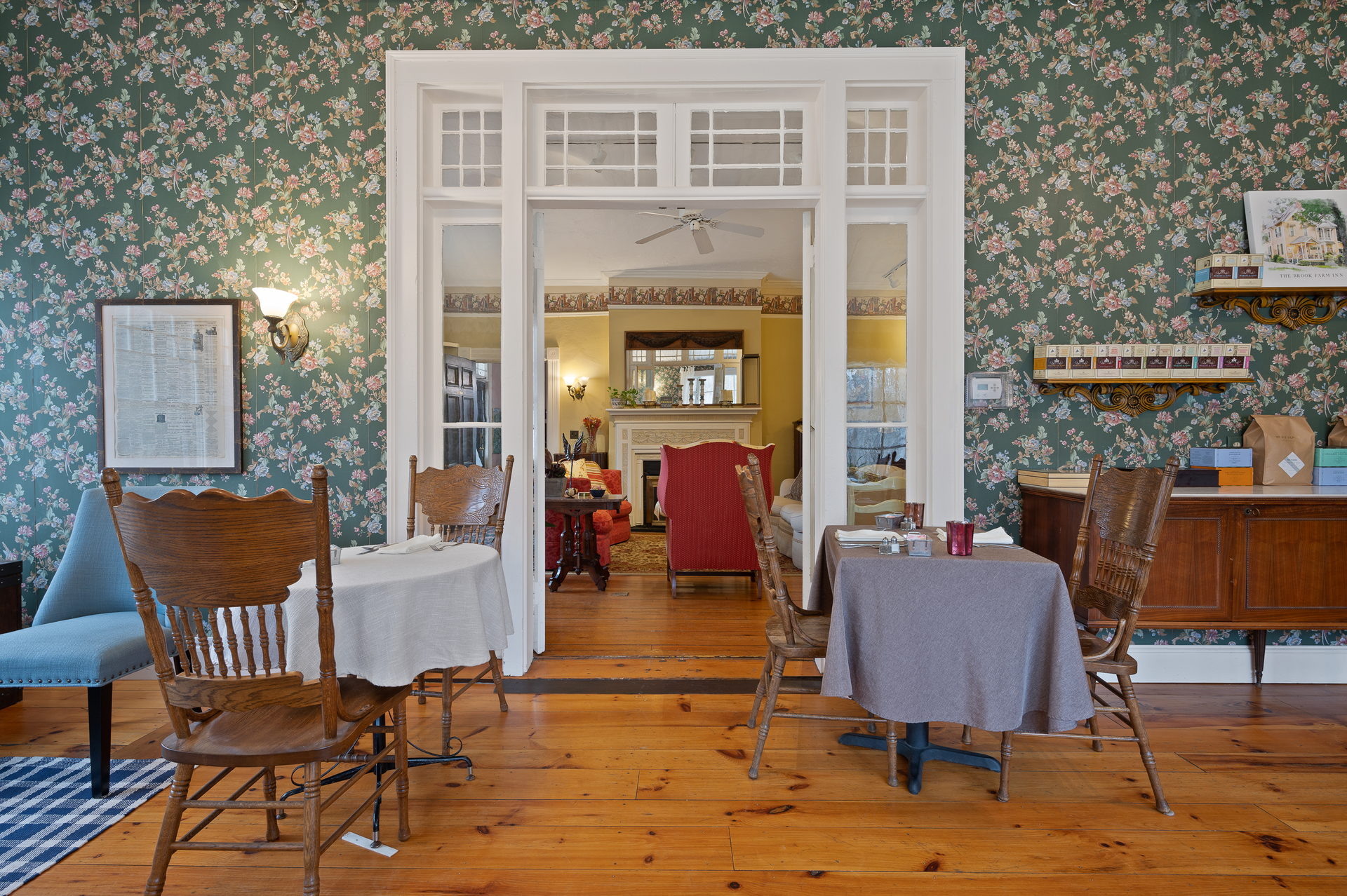 A dining room with tables and chairs and floral wallpaper