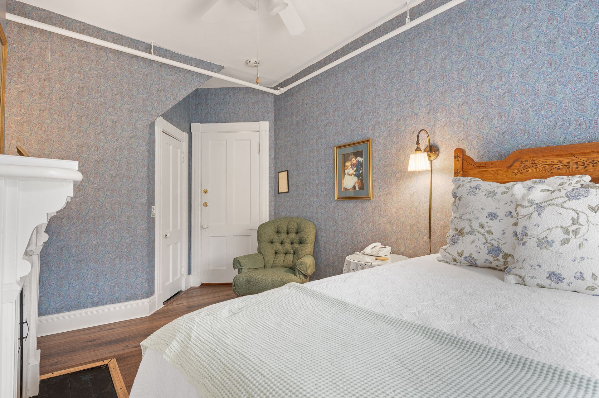 A bedroom with a bed , chair and fireplace.