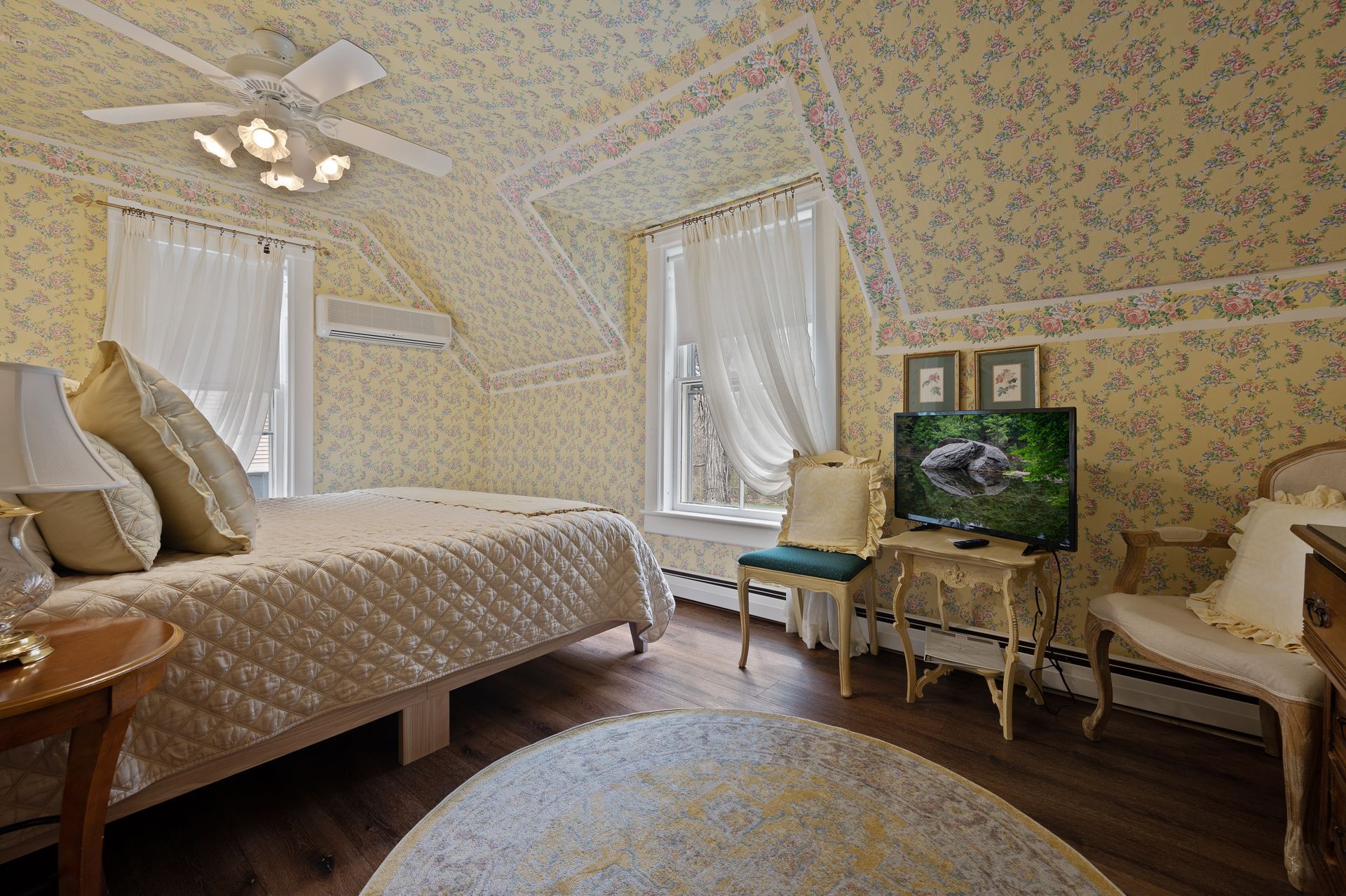 A bedroom with two beds , a chair , a table and a television.