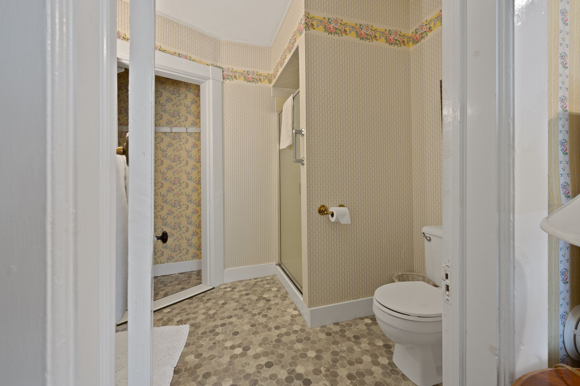 A bathroom with a toilet , shower , and mirror.