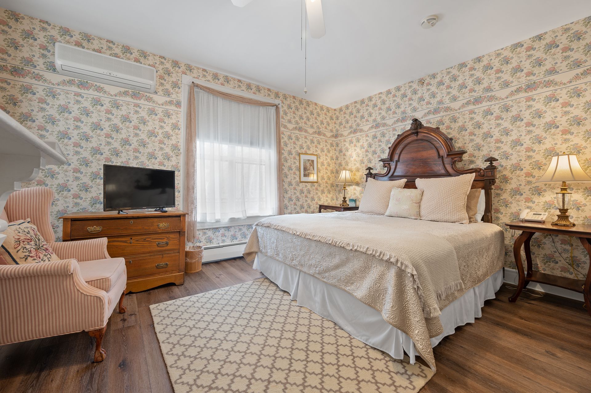 A bedroom with a king size bed , dresser , chair and television.