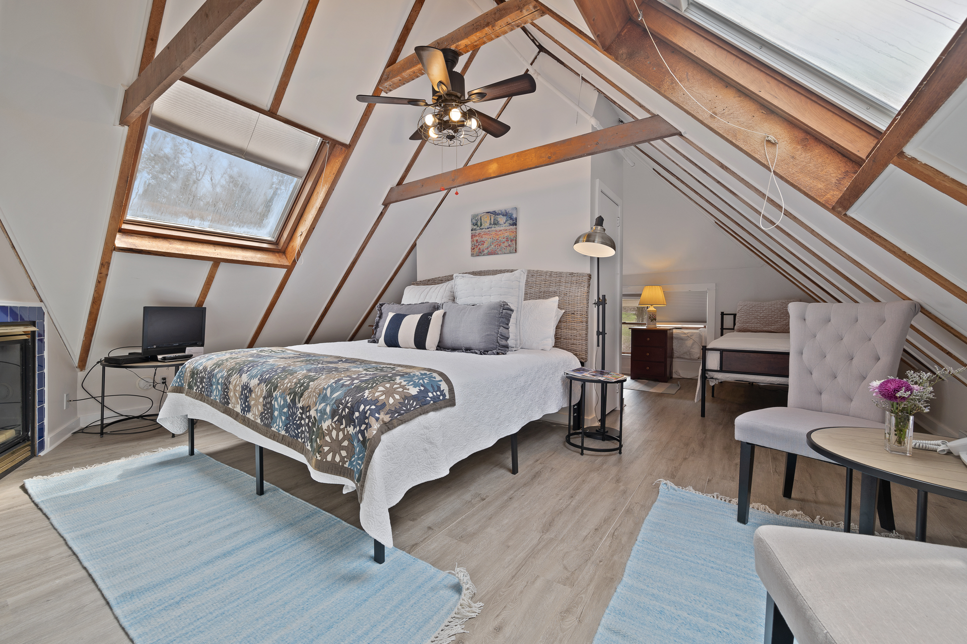 A bedroom with a bed , chairs , and a ceiling fan.