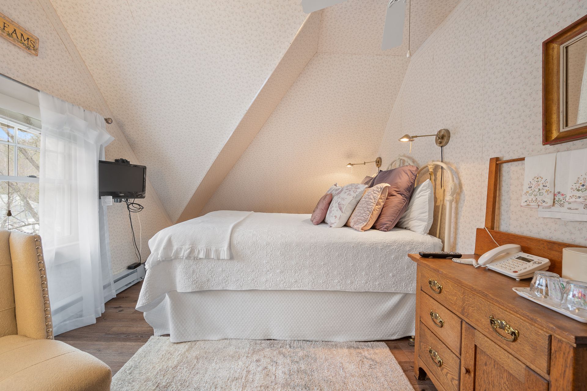 A bedroom with a bed , dresser , chair and television.