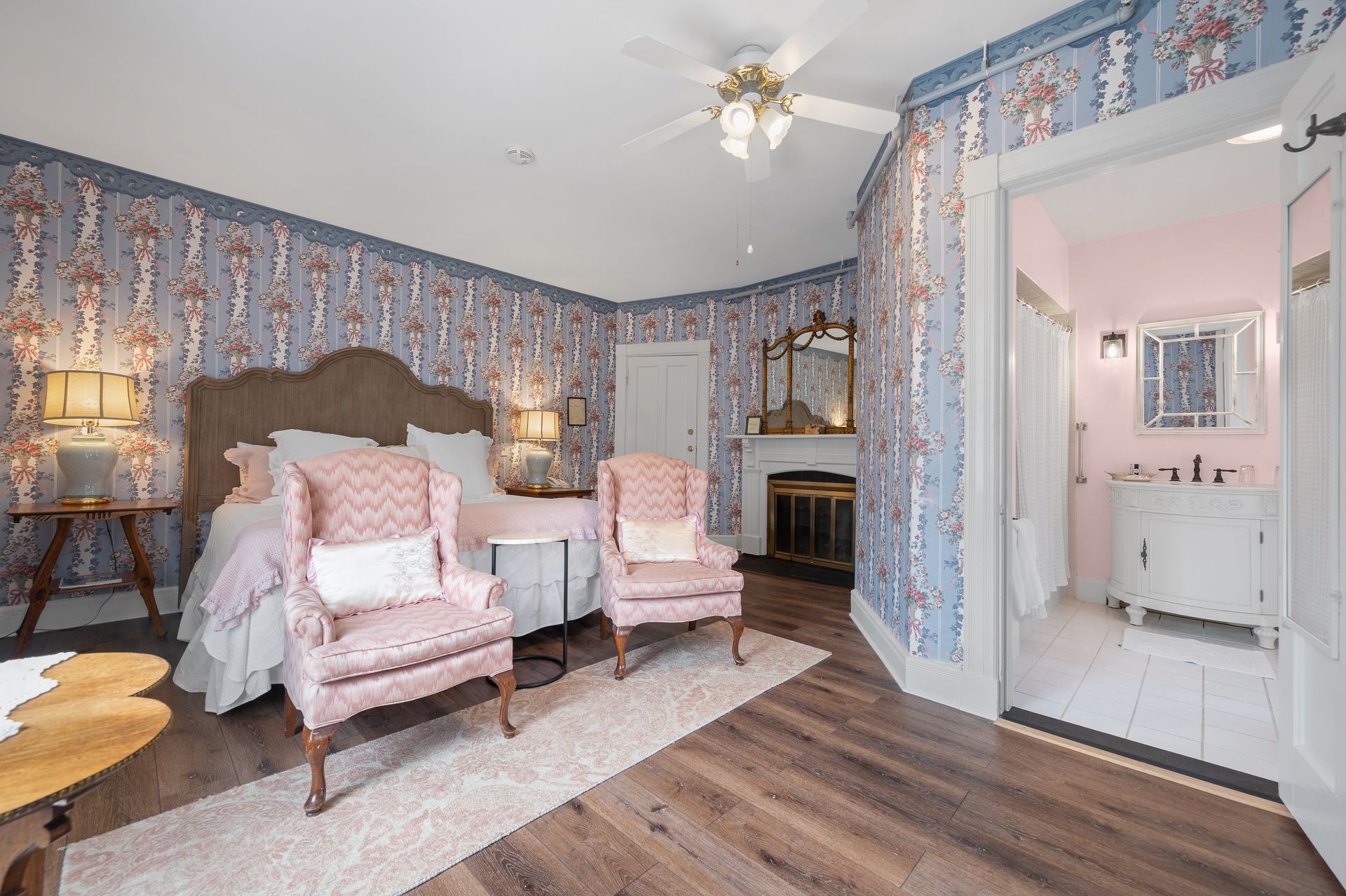 A bedroom with a bed , chairs , and a ceiling fan.