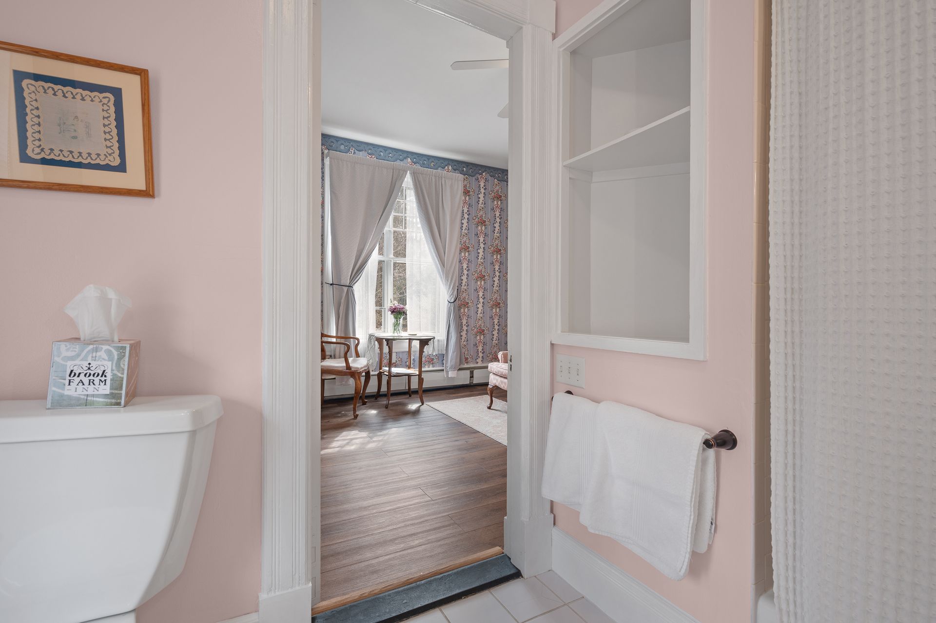 A bathroom with a toilet , towel rack , and a picture on the wall.