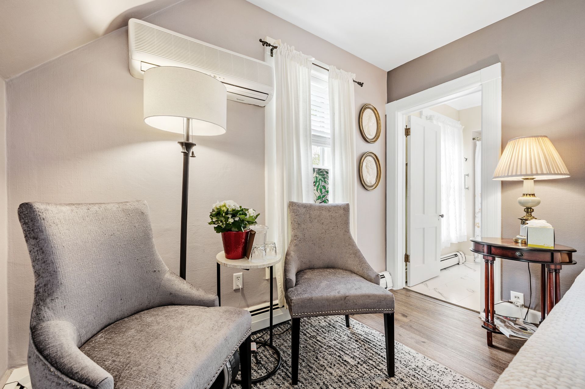 A living room with two chairs , a lamp , and a table.
