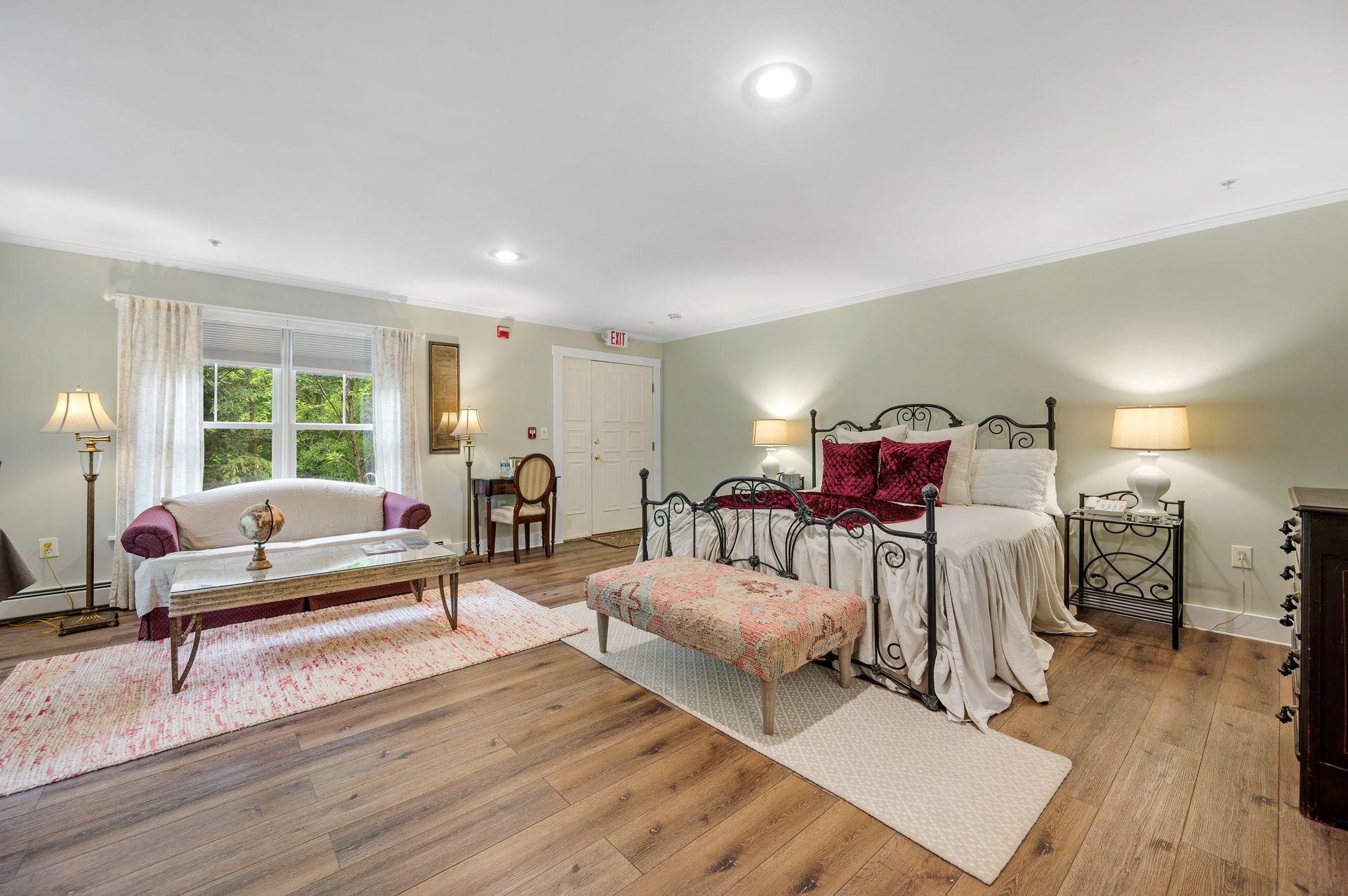 A bedroom with a king size bed , a couch , a table , and a window.