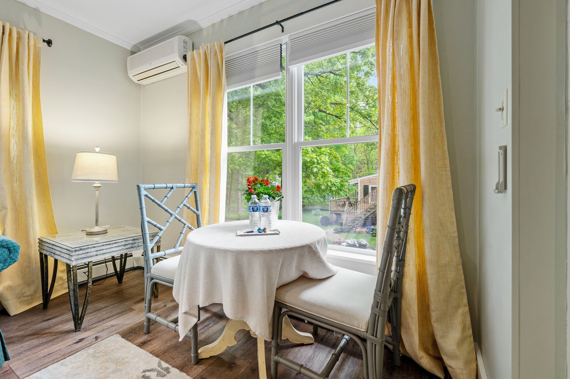 A room with a table and chairs in front of a window.