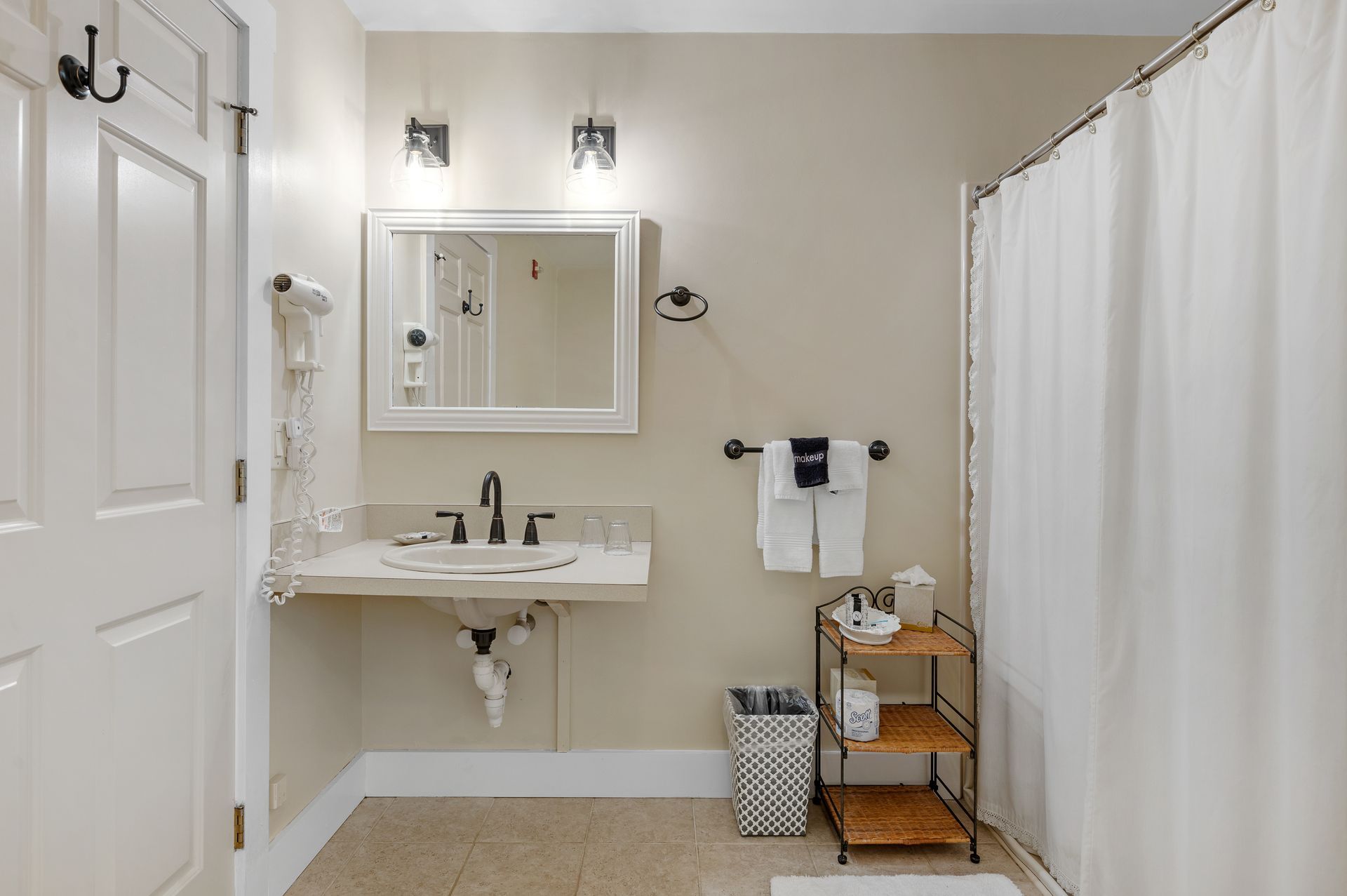 A bathroom with a sink , mirror , and shower curtain.