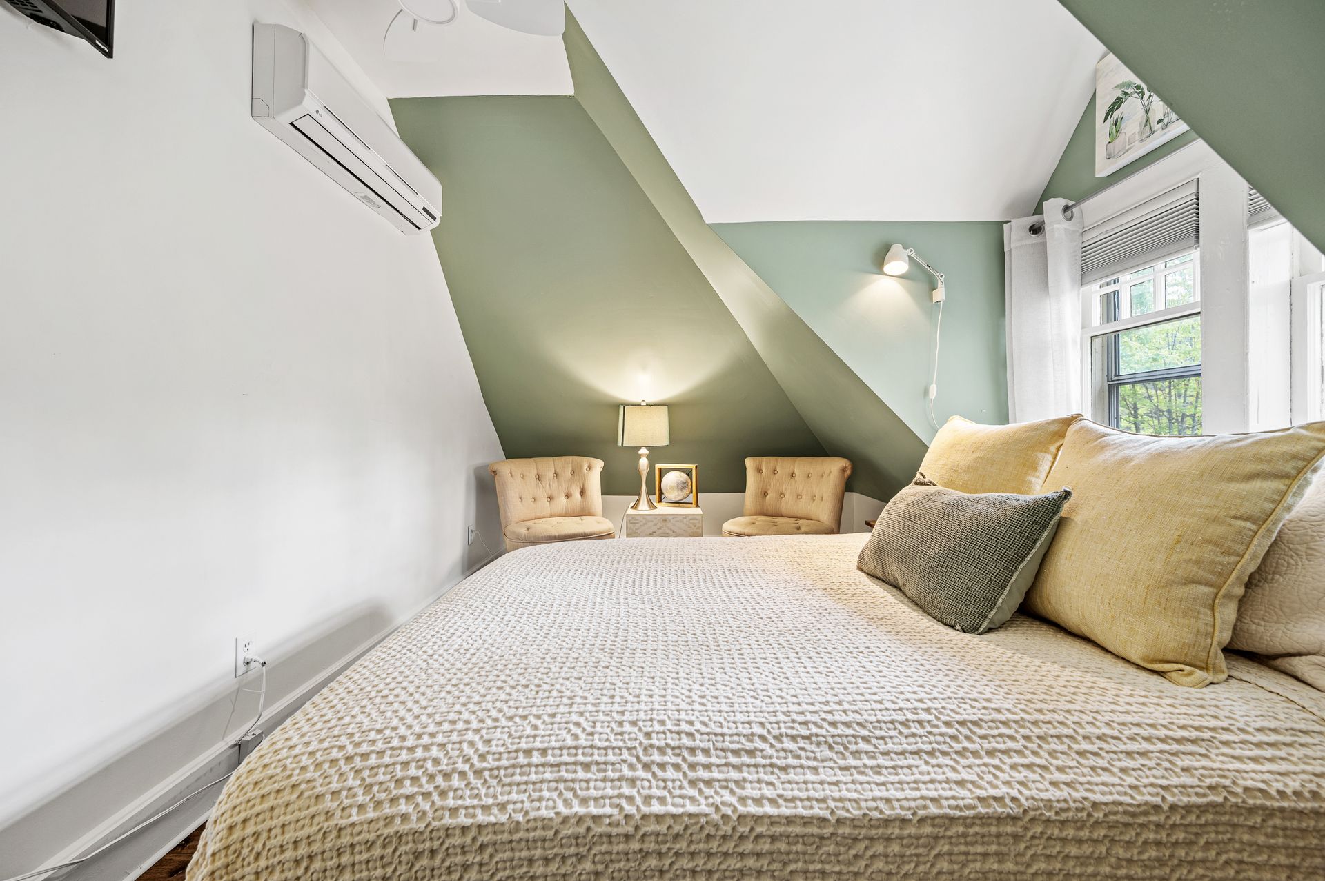 A bedroom with a bed , chairs and a window.