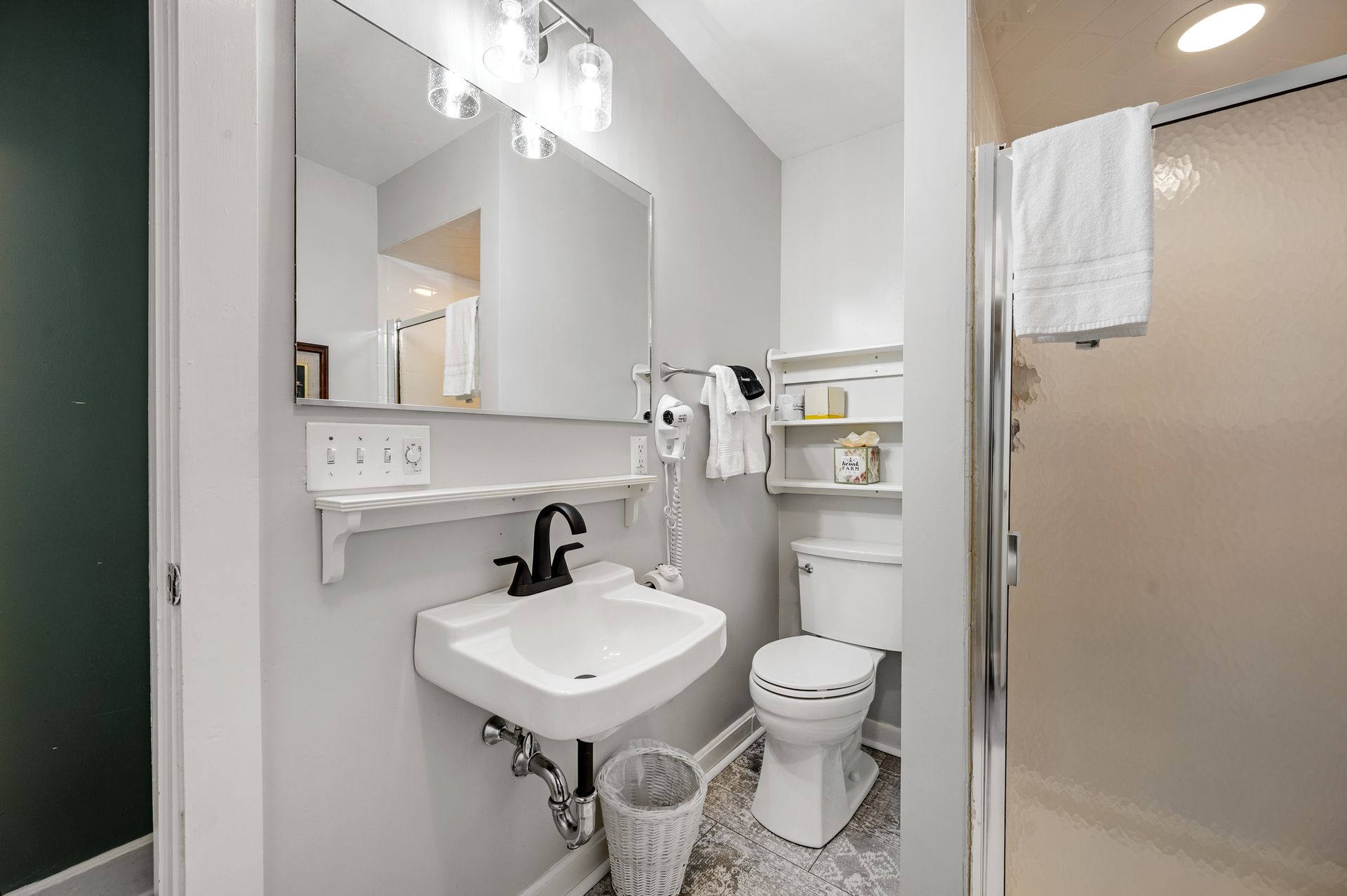 A bathroom with a sink , toilet , mirror and shower.