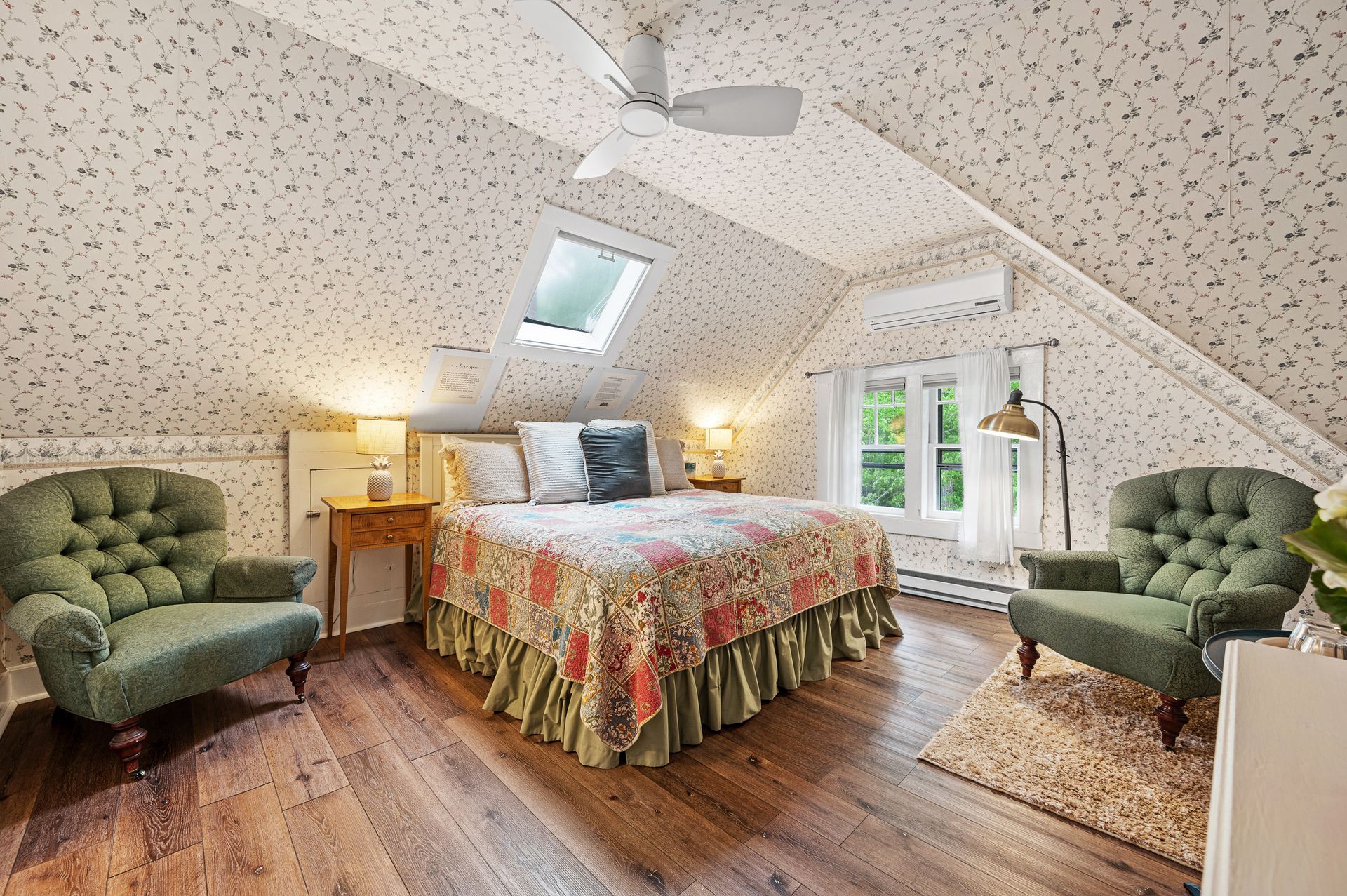 A bedroom with a bed , chairs and a ceiling fan.