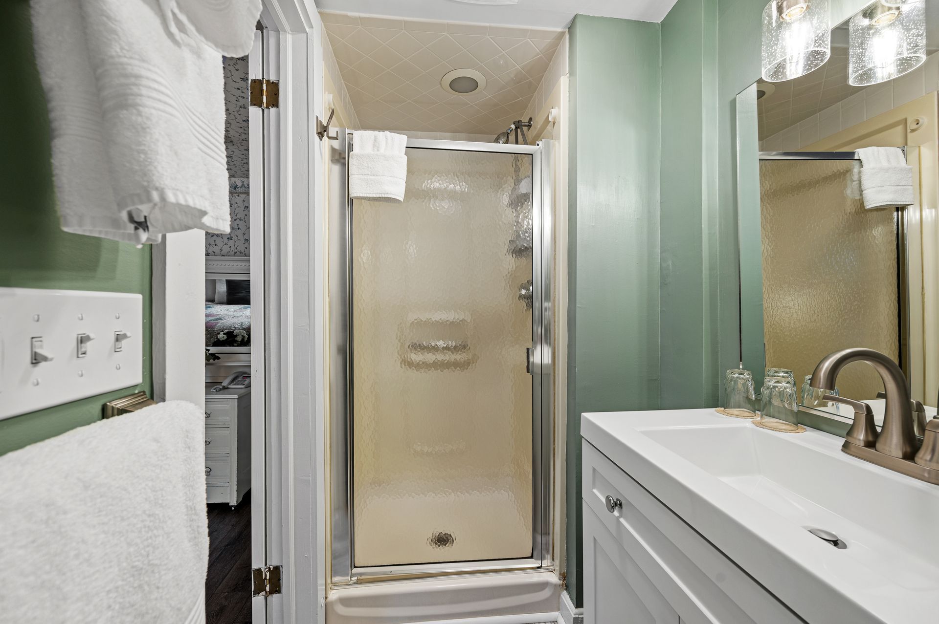 A bathroom with a shower , sink and mirror.
