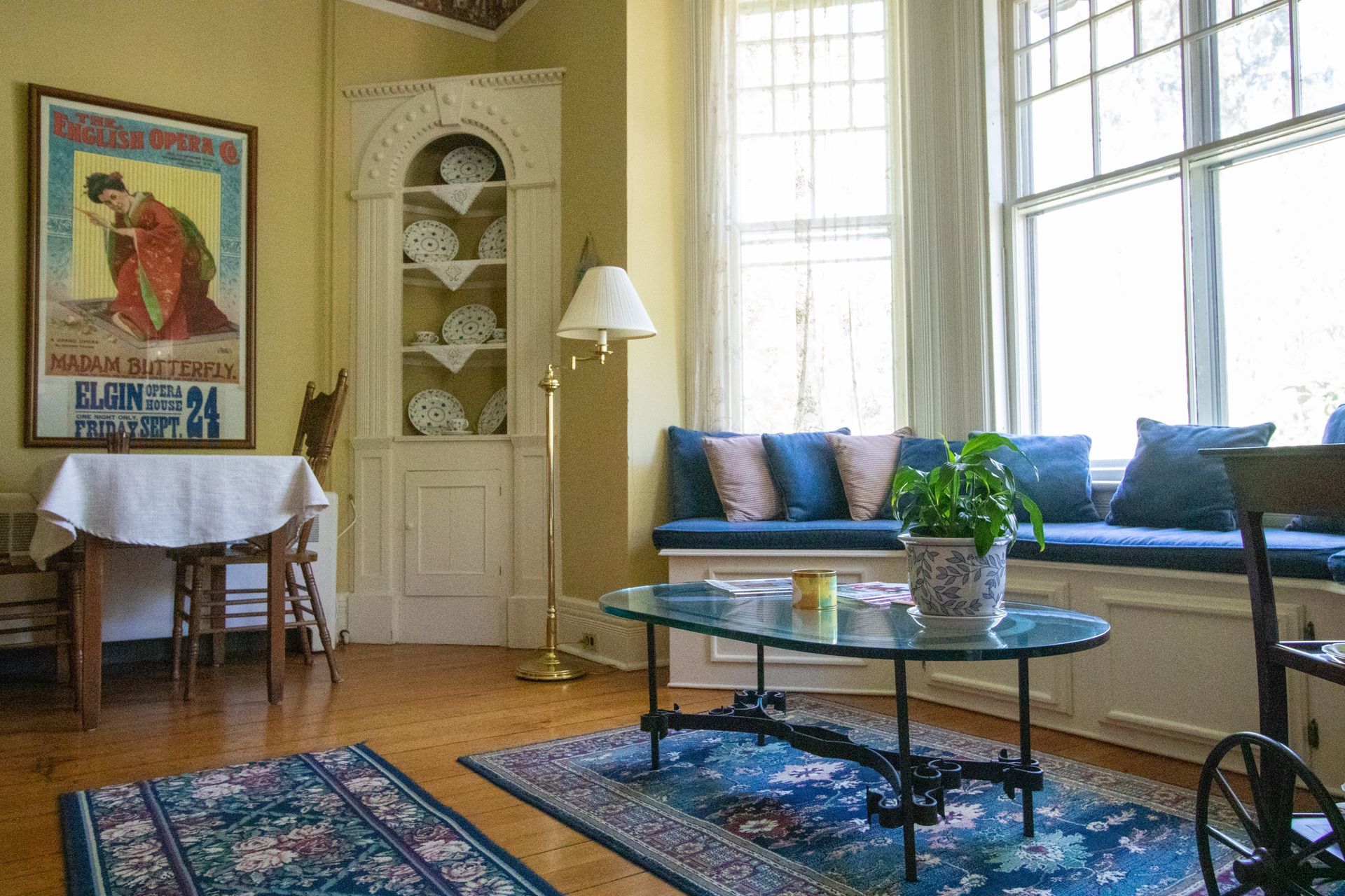 A living room with a glass coffee table and a picture on the wall