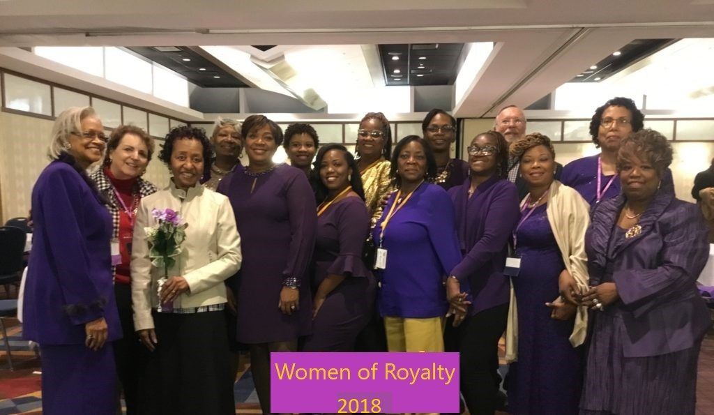 A group of women are posing for a picture with a sign that says woman of royalty