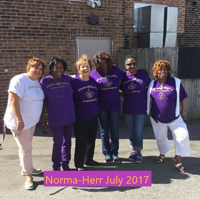 A group of women wearing purple shirts are posing for a picture in july 2017