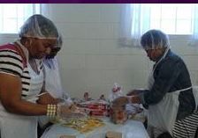 A group of people are standing around a table preparing food.