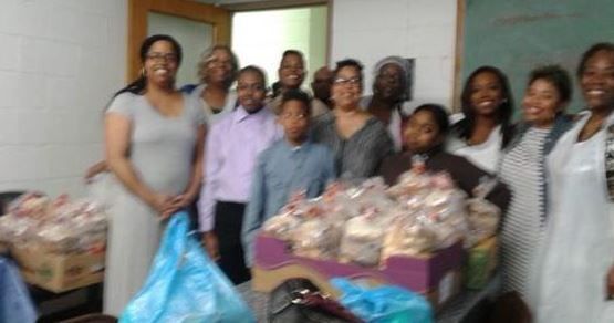 A group of people are posing for a picture with bags of food