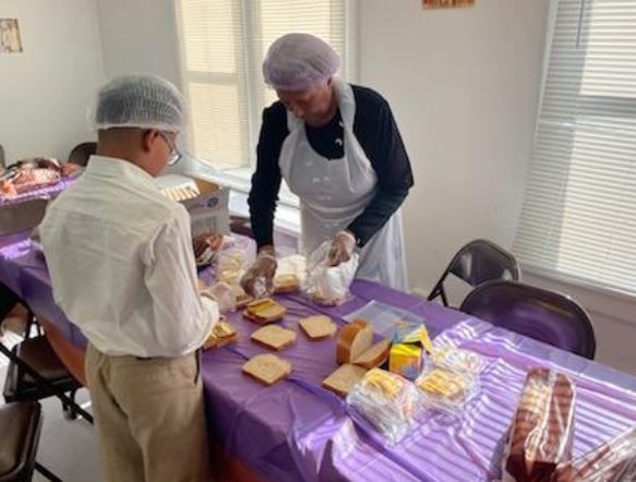 A man and a woman are preparing food at a table