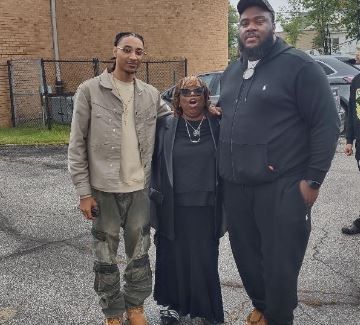 Three people are posing for a picture in a parking lot.