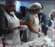 A group of people are standing around a table in a kitchen.