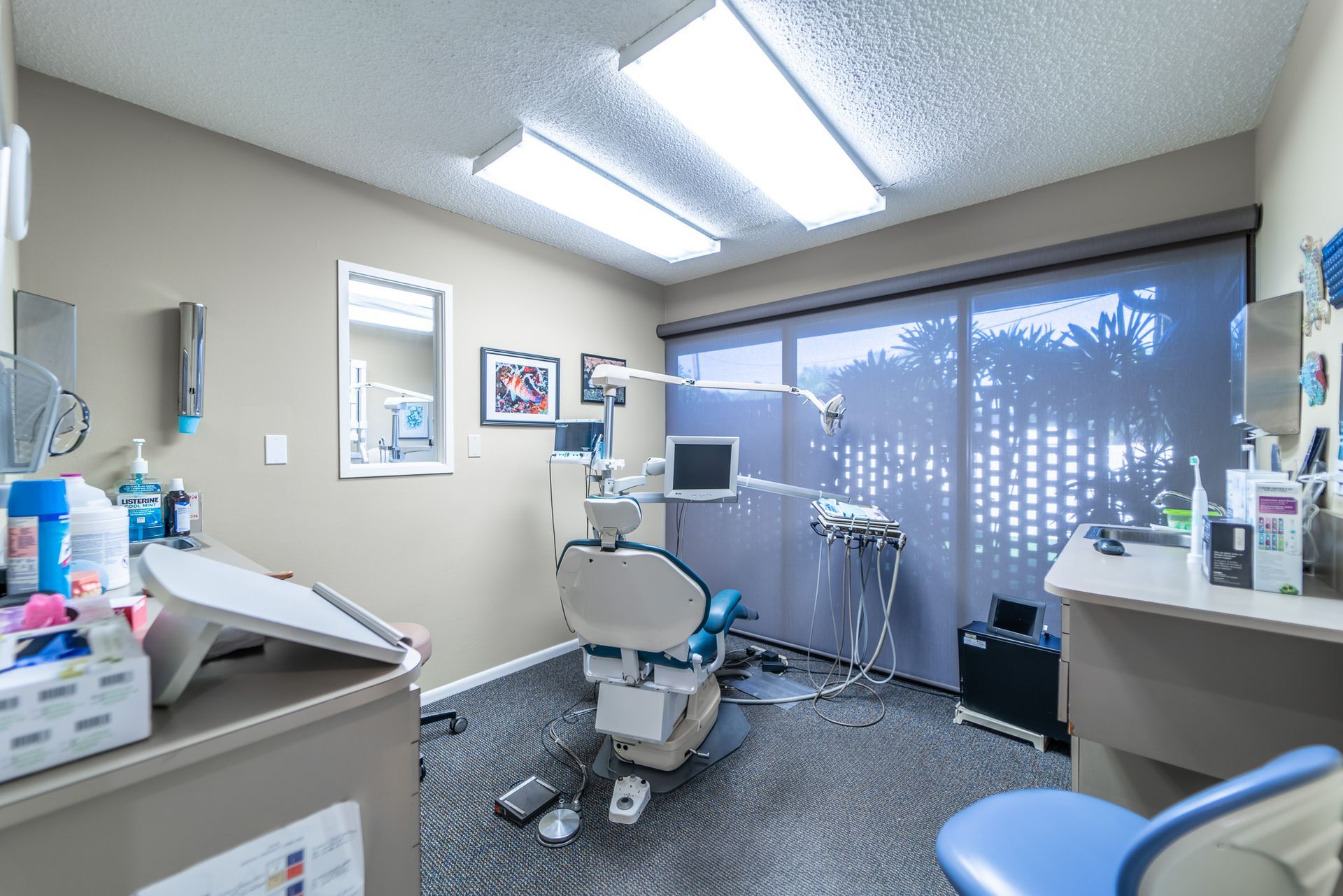 A dental office with a blue dental chair and a large window.
