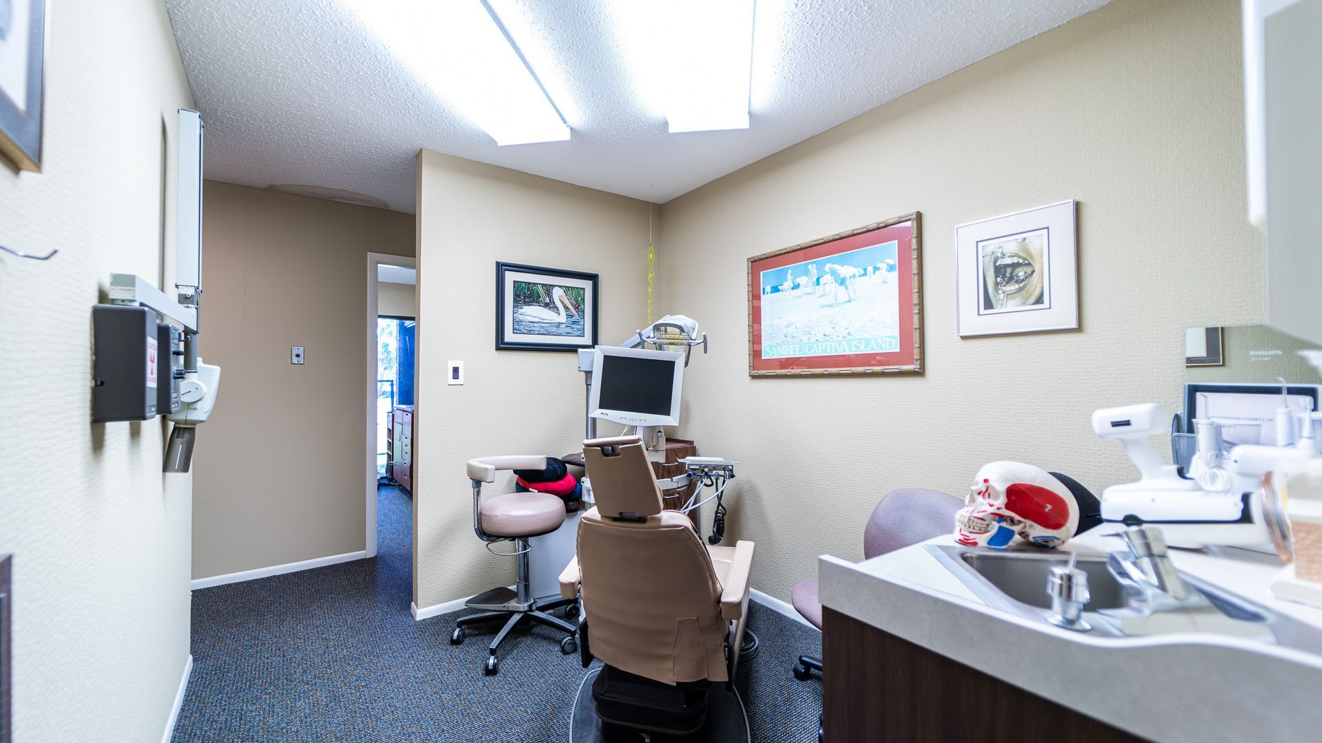 A dental office with a dental chair and a sink.
