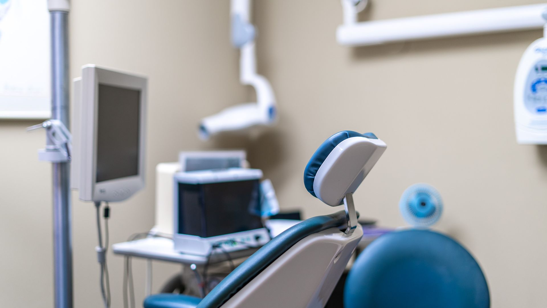 A dental office with a dental chair and a monitor.
