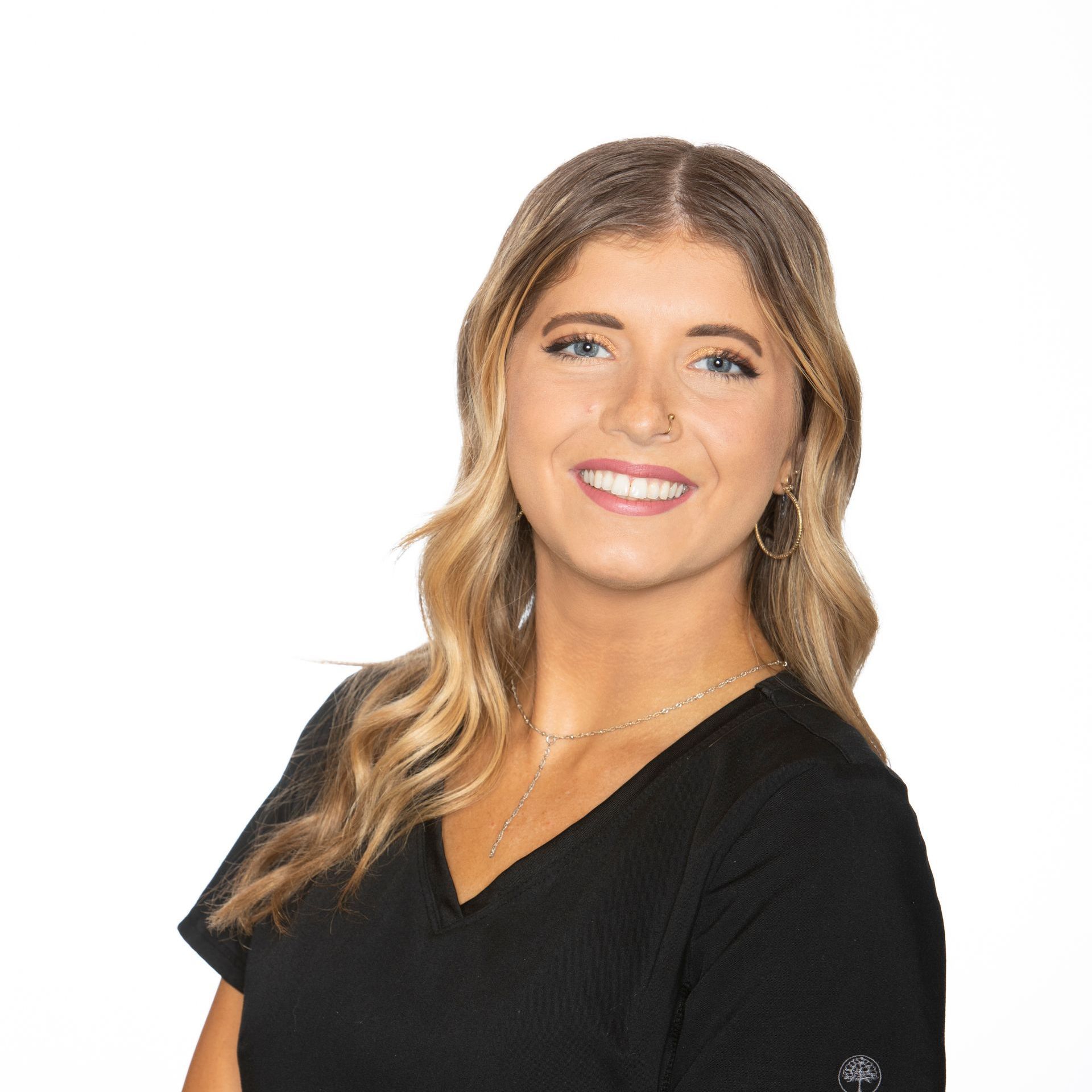 A woman in a black scrub top is smiling for the camera.