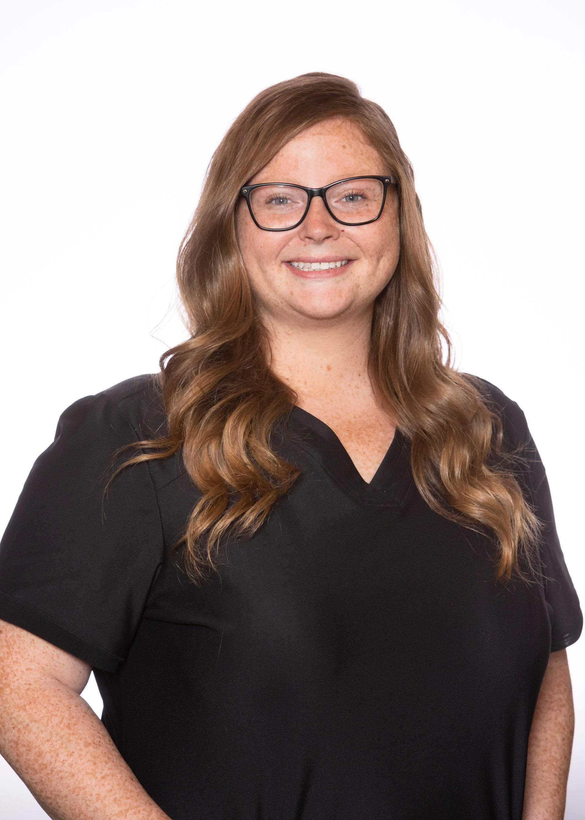 A woman wearing glasses and a black shirt is smiling for the camera.
