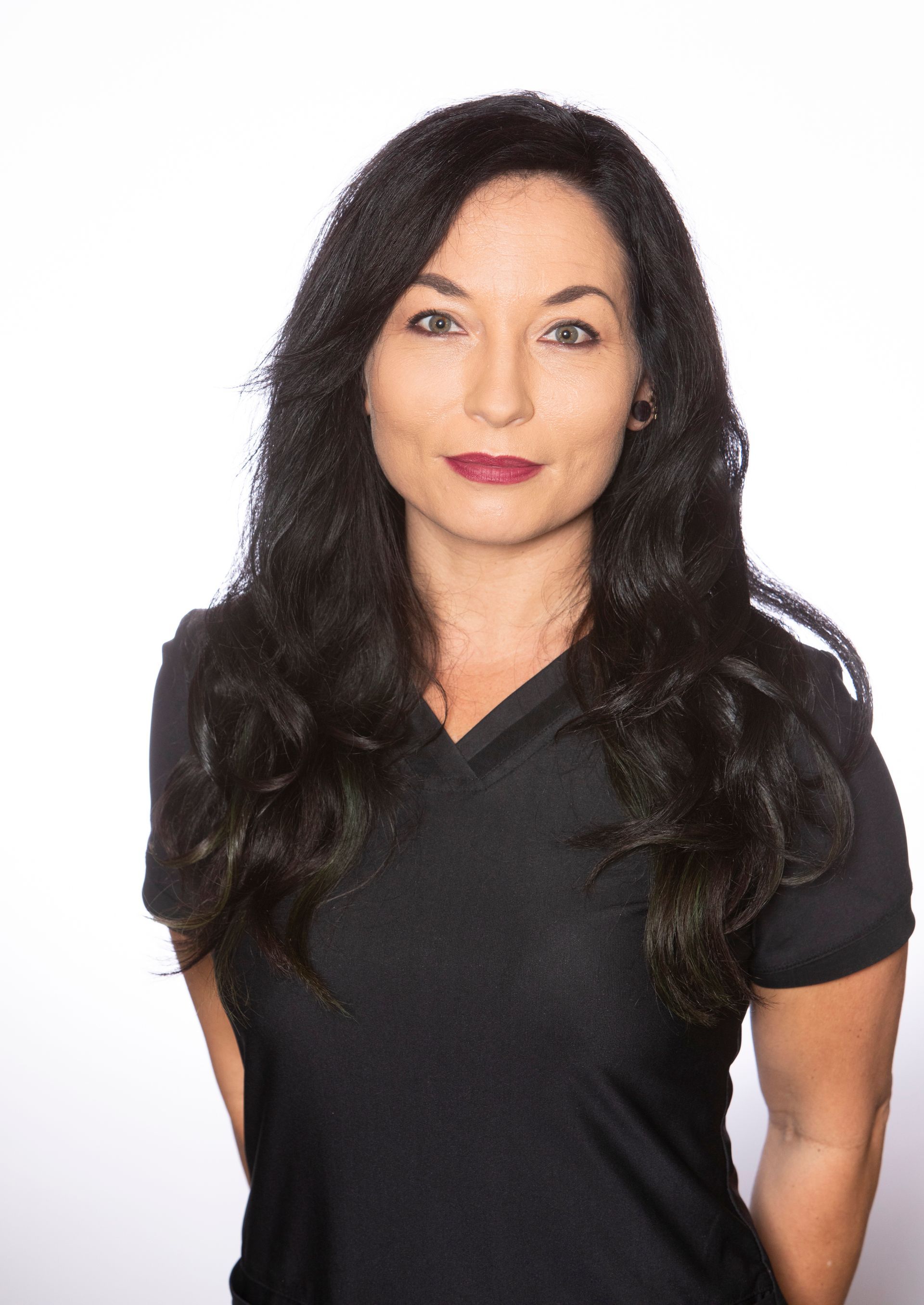 A woman with long black hair is wearing a black shirt and red lipstick.