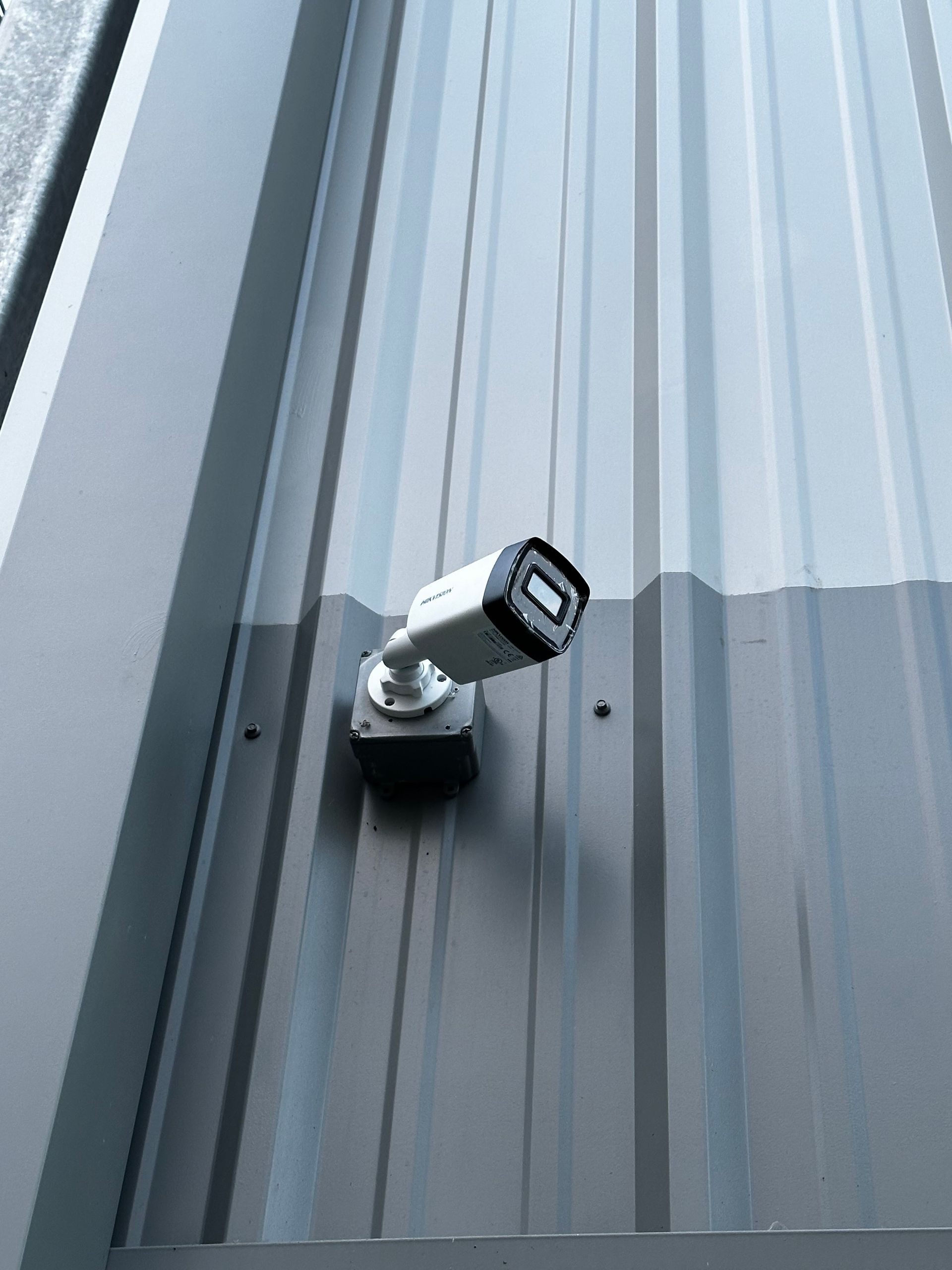 Security camera mounted on a gray metal wall.