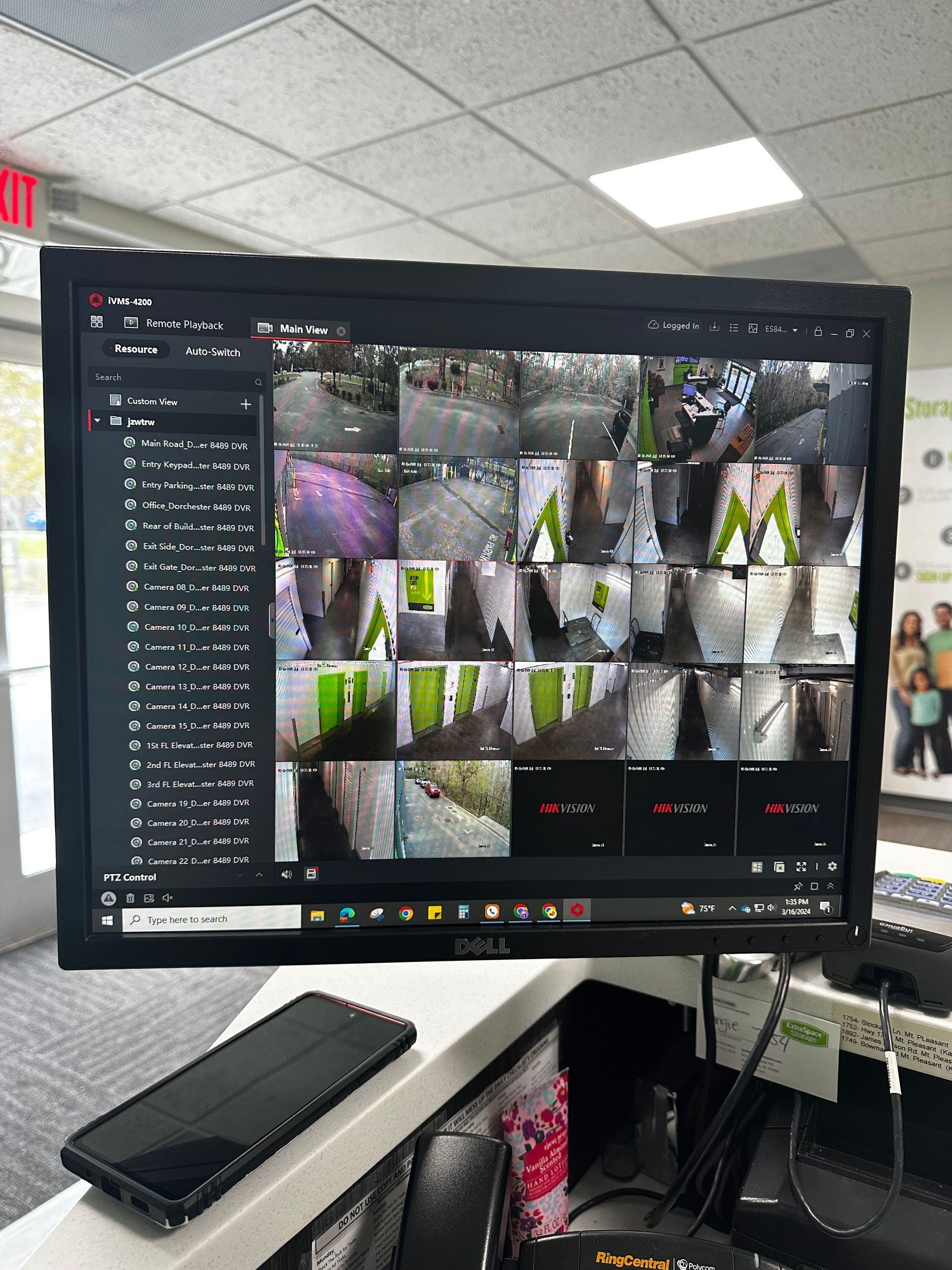 Security camera monitor displaying multiple views of an exterior location. Black phone on a counter in front.