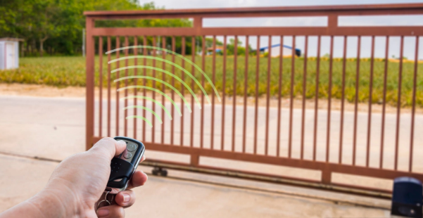 Hand holding a remote controlling a brown gate. Signal waves arc out from remote towards the gate.