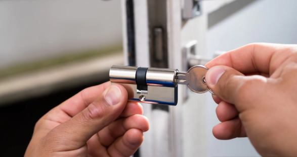 Hands inserting key into silver door lock.