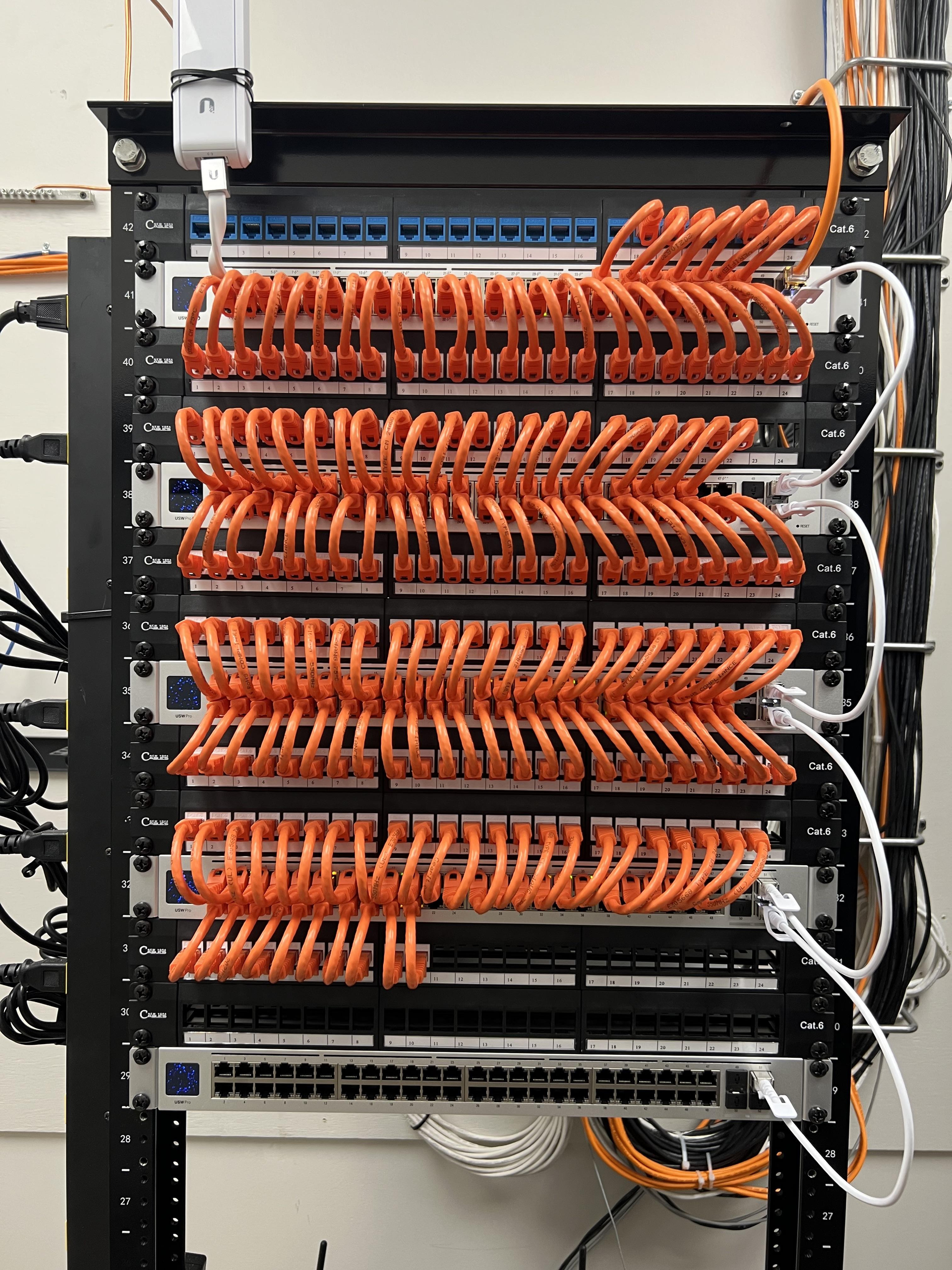 Network server rack with orange Ethernet cables neatly organized.