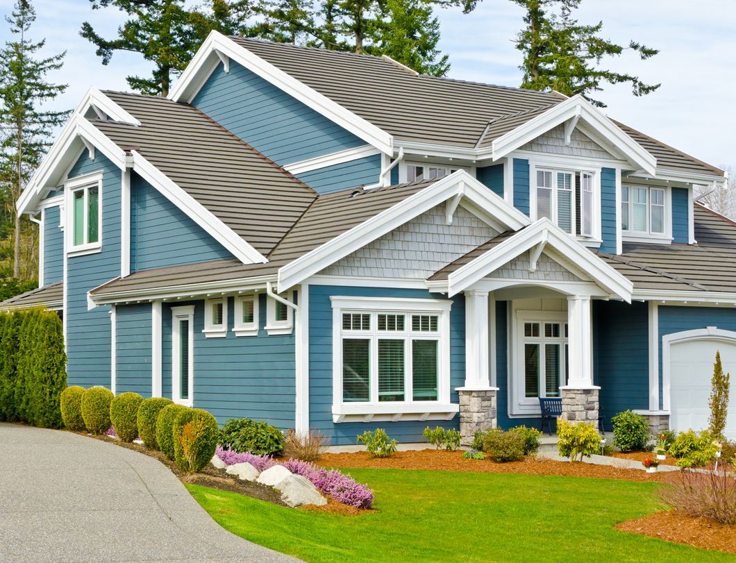 A large blue house with white trim, gabled roof, and a front porch.