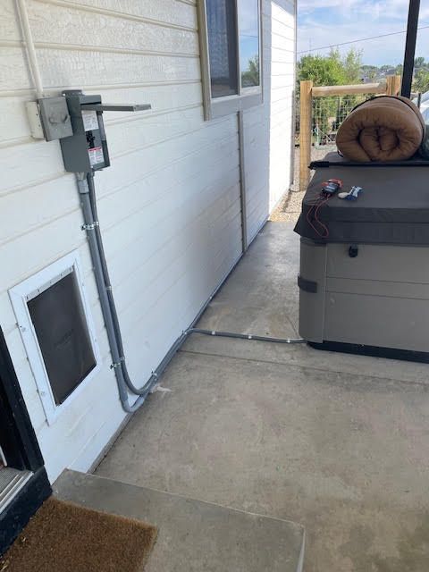 Exterior view: Electrical box and conduit next to a house with a hot tub and steps.